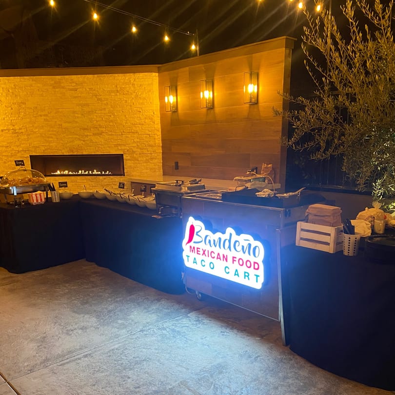 Bandeño Mexican Food taco cart with a glowing sign, buffet, and fireplace at night.