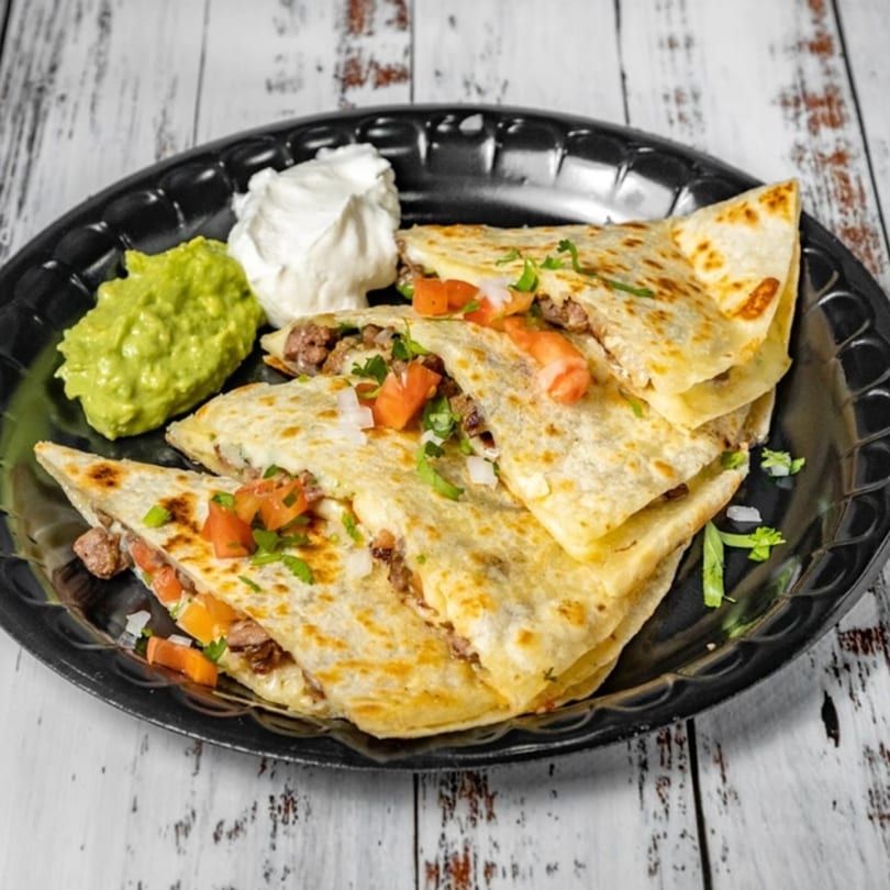 Bandeño Mexican Food quesadillas with meat, tomatoes, onions, cilantro, guacamole, and sour cream.