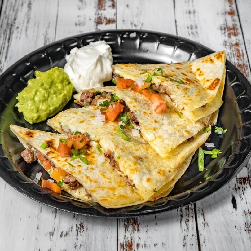 Bandeño Mexican Food quesadillas with meat, tomatoes, onions, cilantro, guacamole, and sour cream.